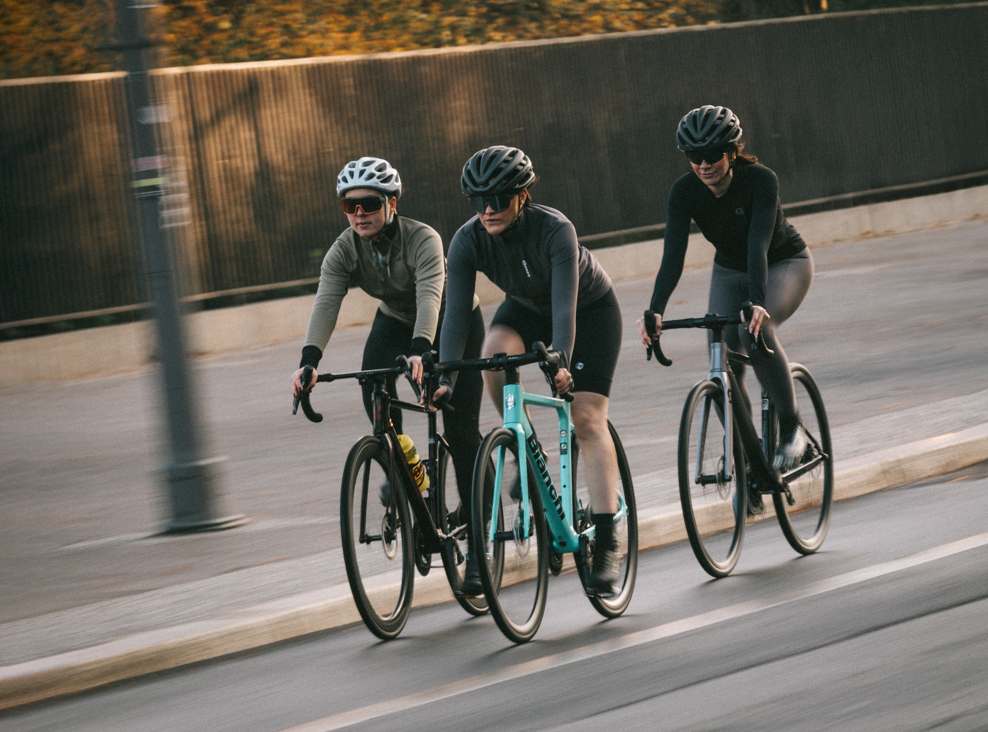 Drei Radfahrerinnen in Sportkleidung fahren gemeinsam auf einer städtischen Straße.